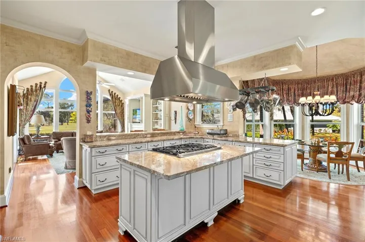 Kitchen with a center island, stainless steel gas cooktop, ornamental molding, a peninsula, and island exhaust hood