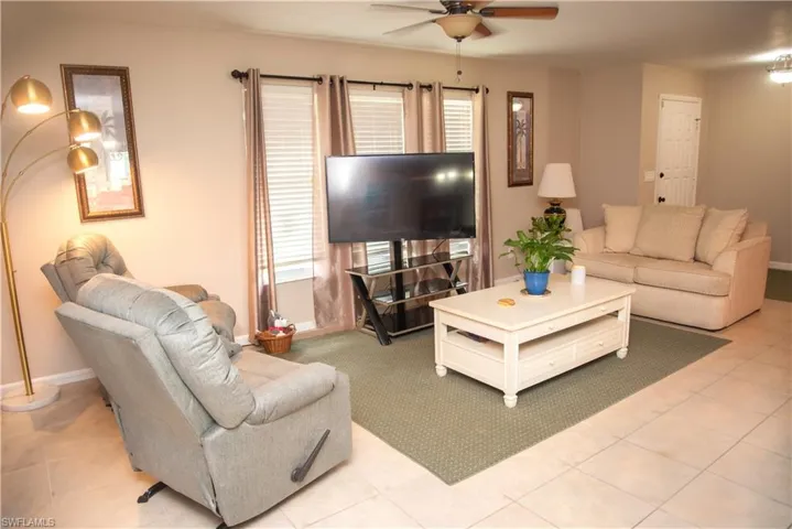 Living room with a healthy amount of sunlight, light tile patterned floors, and ceiling fan