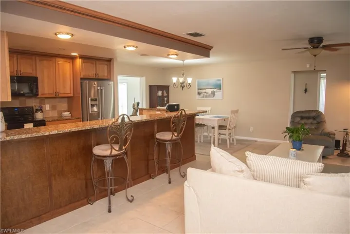 Kitchen featuring tasteful backsplash, light stone counters, high end fridge, stove, and a kitchen bar