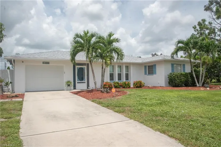 Single story home with a garage and a front lawn