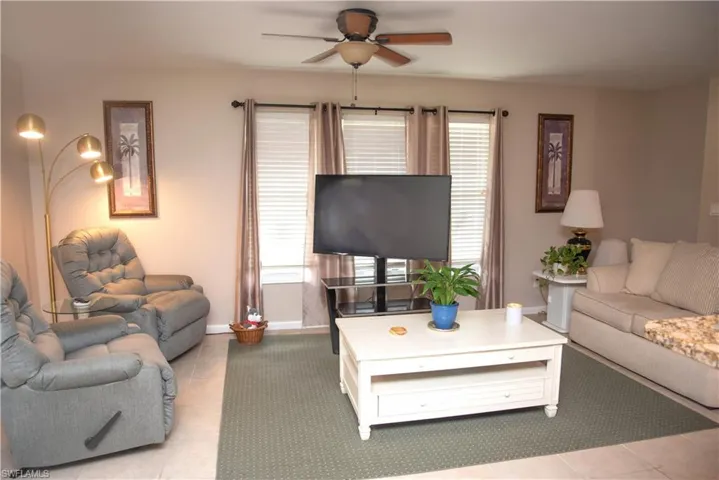 Tiled living room with a healthy amount of sunlight and ceiling fan