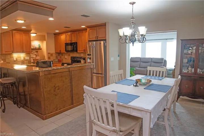 Kitchen featuring a chandelier, hanging light fixtures, range, light tile patterned floors, and backsplash
