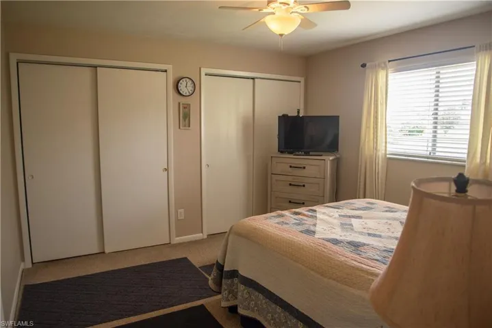Bedroom featuring light carpet, multiple closets, and ceiling fan
