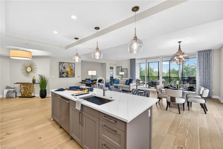 Large open space, kitchen with gray cabinetry, pendant lighting, and light stone counters, the open floor plan has nice flow through the dining and living room area