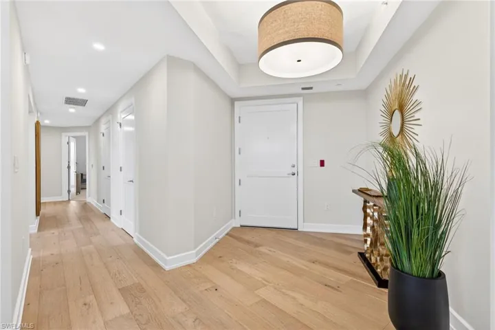 Large foyer entrance with light wood-style floors and recessed lighting