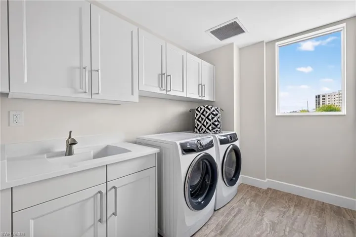 Spacious laundry room area with full size washer and clothes dryer and plenty of cabinet space