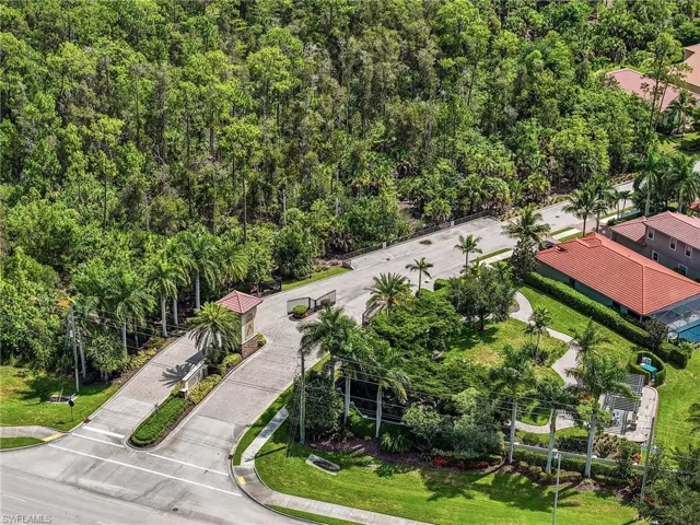 Aerial perspective showcasing a community gated entrance with a decorative gatehouse and multiple palm trees