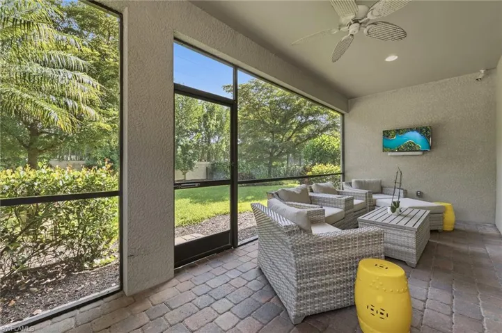Screened patio featuring paver flooring, a textured stucco wall, and a ceiling fan