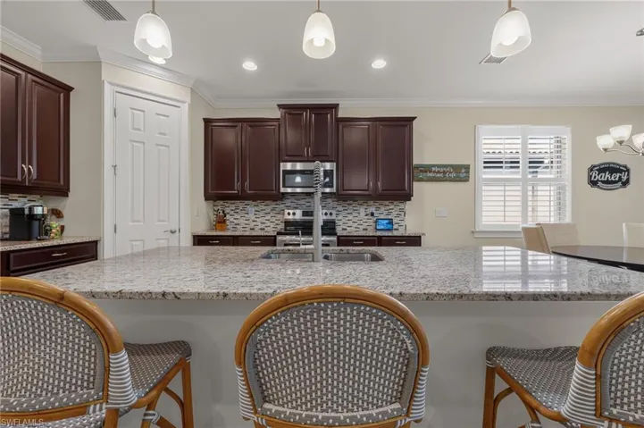 Expansive kitchen island featuring a granite countertop and an undermount stainless steel sink