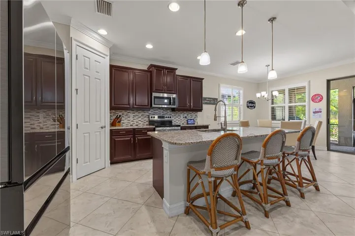 Kitchen featuring a large central island with a granite countertop, pendant lighting, and tile flooring
