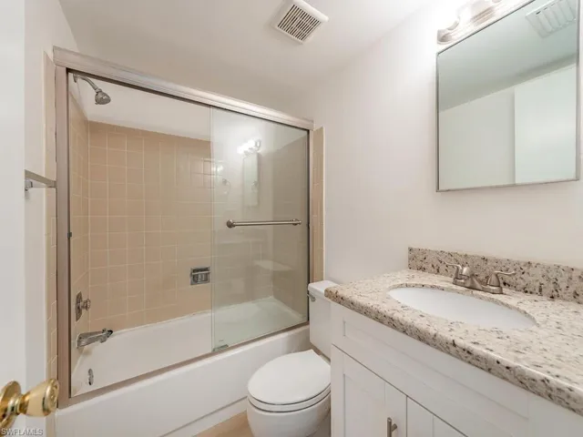 Full bath with vanity, toilet, and combined bath / shower with glass door