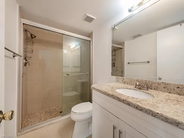 Bathroom featuring a stall shower, vanity, toilet, and tile patterned floors