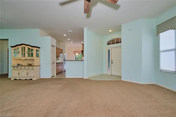 Unfurnished living room with a ceiling fan, light colored carpet, and recessed lighting