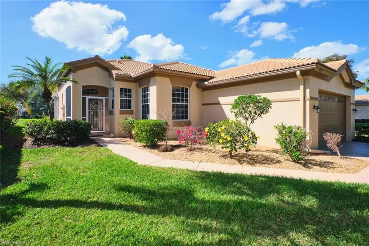 Mediterranean / spanish home with a garage, stucco siding, a front yard, a tiled roof, and driveway