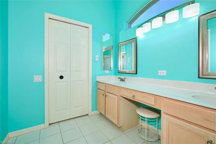 Bathroom with double vanity, light tile patterned floors, and a closet