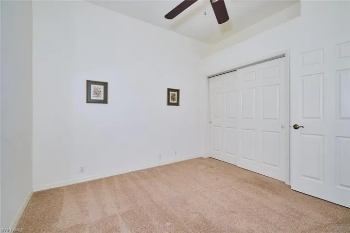 Unfurnished bedroom featuring light colored carpet, a closet, and a ceiling fan