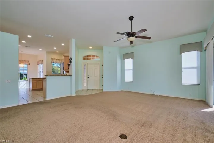 Unfurnished living room featuring light carpet, ceiling fan, and recessed lighting