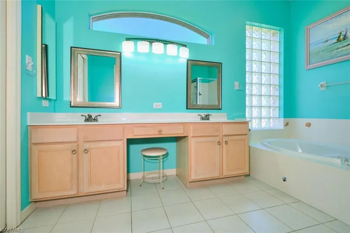 Bathroom with double vanity, a garden tub, and light tile patterned floors
