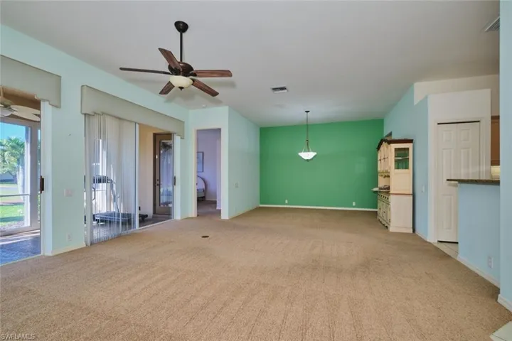 Unfurnished living room featuring ceiling fan and light carpet