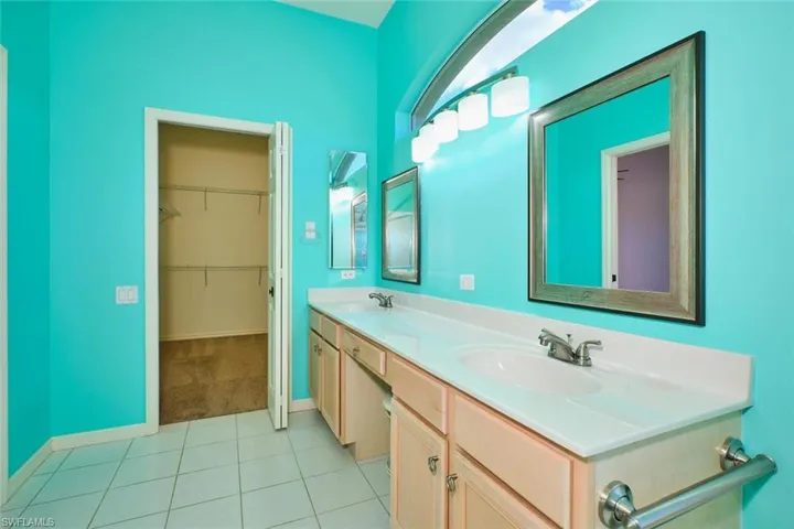 Full bathroom with double vanity, a spacious closet, light tile patterned floors, and light carpet