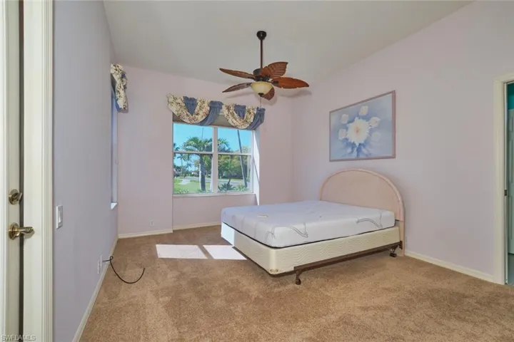 Carpeted bedroom with ceiling fan and baseboards