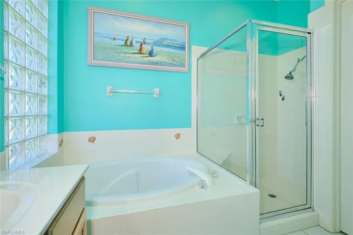 Bathroom featuring vanity, a bath, and a stall shower
