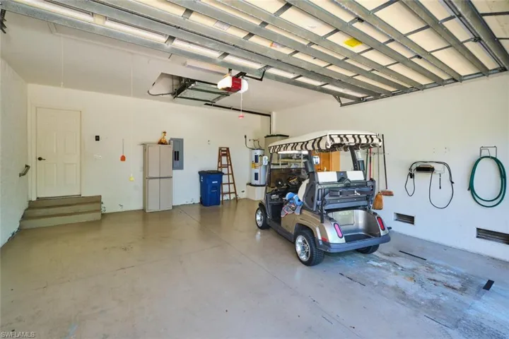 Garage featuring electric panel, a garage door opener, and electric water heater