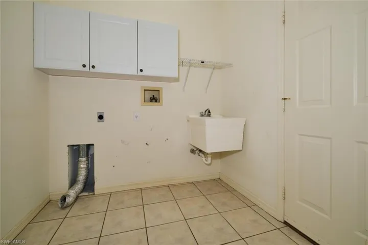 Laundry area featuring cabinet space, hookup for an electric dryer, light tile patterned floors, and hookup for a washing machine