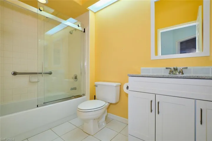 Full bath with vanity, light tile patterned floors, and shower / bath combination with glass door