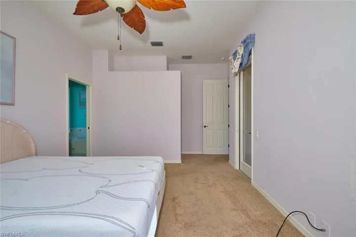 Bedroom with light colored carpet, a ceiling fan, and connected bathroom