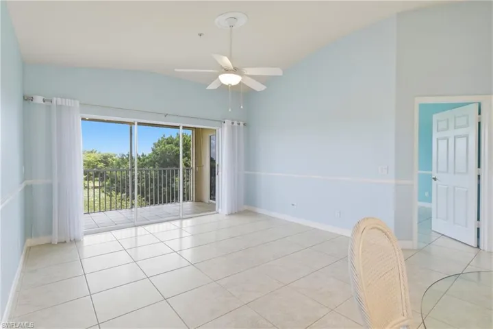 Spare room featuring lofted ceiling, ceiling fan, and light tile patterned flooring