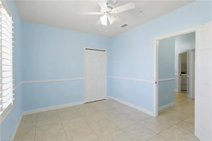 Empty room with a ceiling fan and light tile patterned flooring