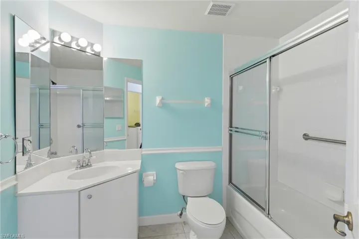 Bathroom featuring vanity, shower / bath combination with glass door, and light tile patterned flooring