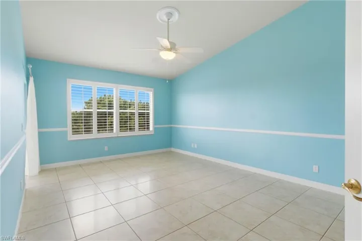 Empty room with a ceiling fan and light tile patterned floors