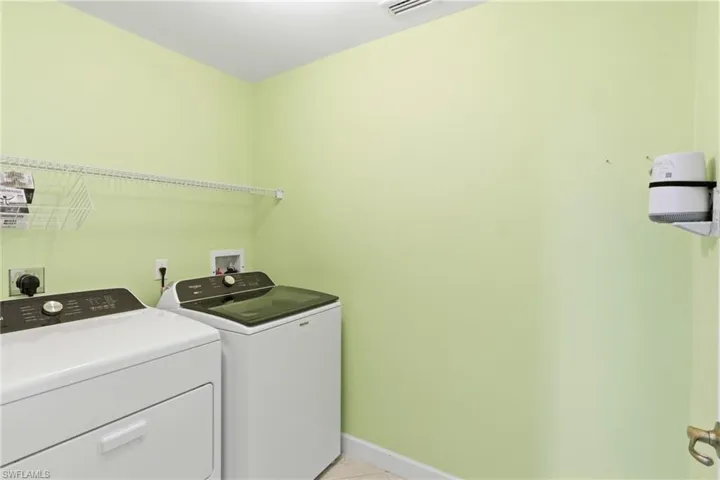 Laundry area featuring washing machine and clothes dryer and light tile patterned floors