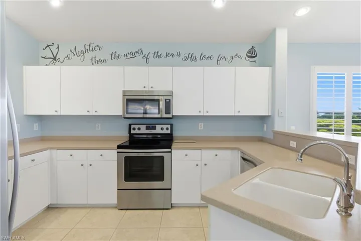 Kitchen with stainless steel appliances, light countertops, white cabinets, and recessed lighting