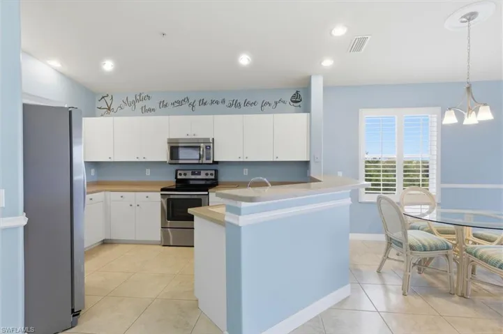 Kitchen with stainless steel appliances, white cabinetry, light countertops, and light tile patterned floors