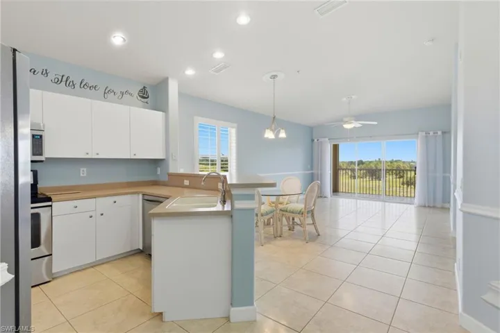 Kitchen with a peninsula, white cabinets, stainless steel appliances, light countertops, and light tile patterned floors