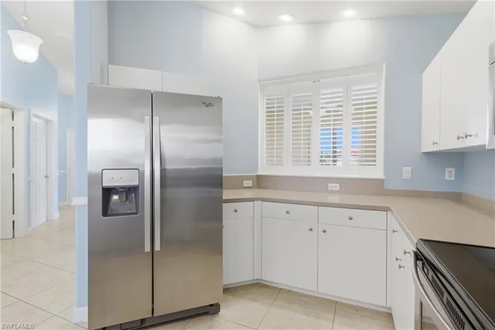 Kitchen featuring stainless steel appliances, light countertops, white cabinets, and light tile patterned flooring