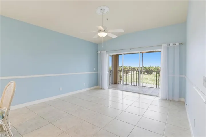 Unfurnished room with lofted ceiling, ceiling fan, and light tile patterned floors
