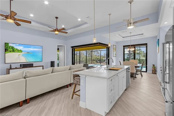 Kitchen featuring sink, white cabinets, a kitchen bar, a kitchen island with sink, and a raised ceiling