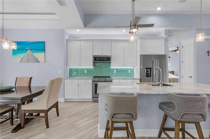 Kitchen with sink, white cabinetry, decorative light fixtures, ceiling fan, and stainless steel appliances