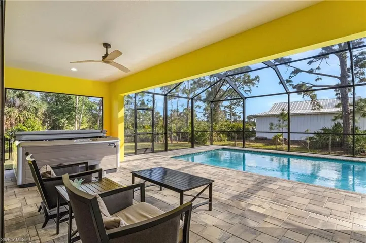 View of swimming pool with ceiling fan, a lanai, a patio area, and a hot tub