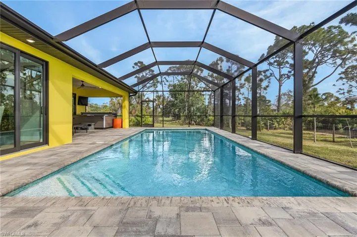 View of pool featuring a hot tub, a patio, a lanai, and ceiling fan