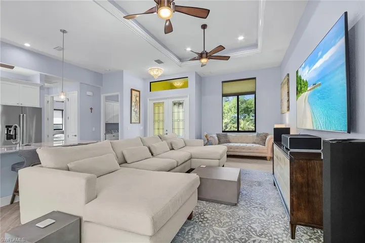 Living room with french doors, ceiling fan, light wood-type flooring, and a tray ceiling