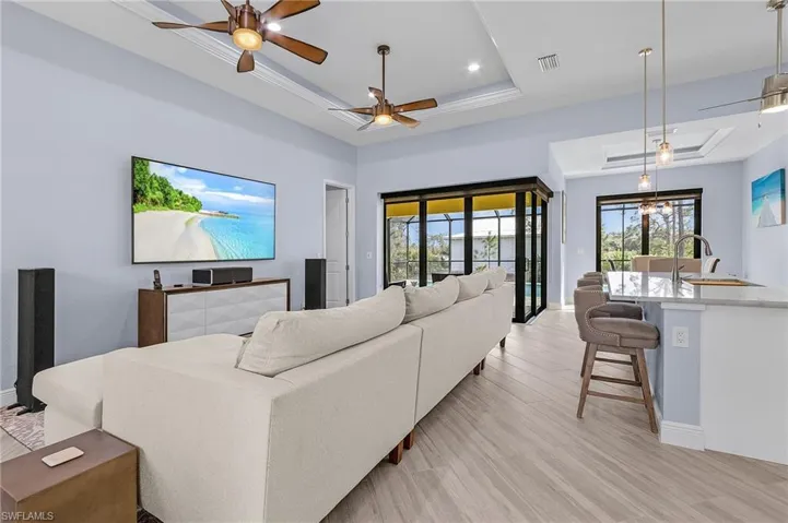 Living room with sink, light hardwood / wood-style floors, a raised ceiling, and ceiling fan
