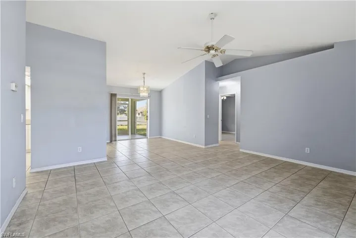 Empty room featuring ceiling fan, light tile patterned floors, vaulted ceiling, and suspended lighting