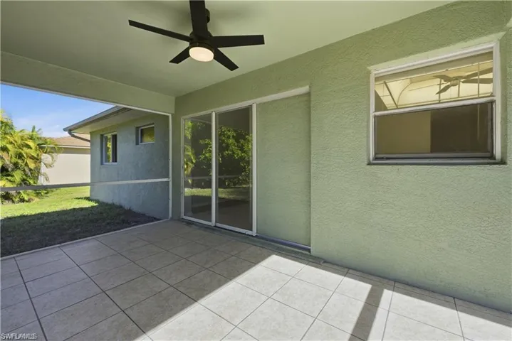 Unfurnished sunroom featuring a ceiling fan, a patio area, and healthy amount of natural light