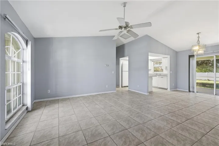 Unfurnished room featuring lofted ceiling, hanging lights, a ceiling fan, and light tile patterned flooring
