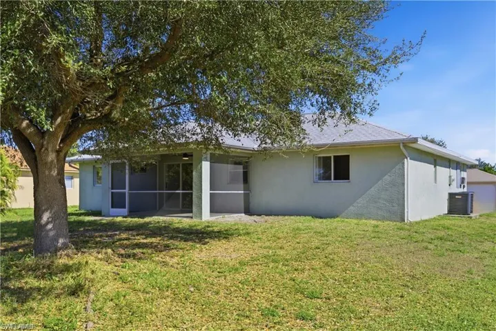 Rear view of house featuring stucco siding, a lawn, and a sunroom